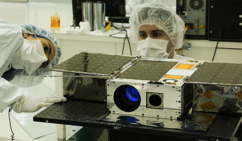 Electrical Test Engineer Esha Murty (left) and Integration and Test Lead Cody Colley (right) prepare the ASTERIA spacecraft for mass properties measurements in April 2017 prior to spacecraft delivery. Image: NASA