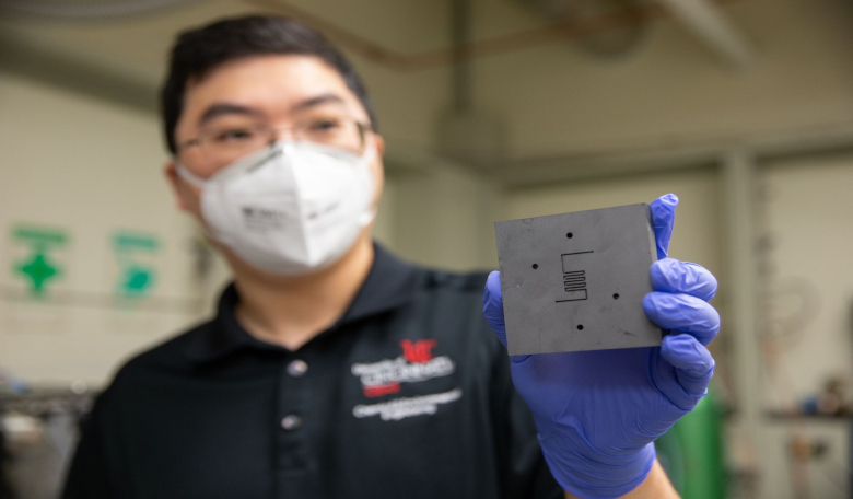 UC chemical engineer Jingjie Wu holds up the reactor where a catalyst converts carbon dioxide into methane; a process that could be used to produce rocket fuel on Mars as well as help mitigate climate change on Earth. Image: Andrew Higley/UC Creative