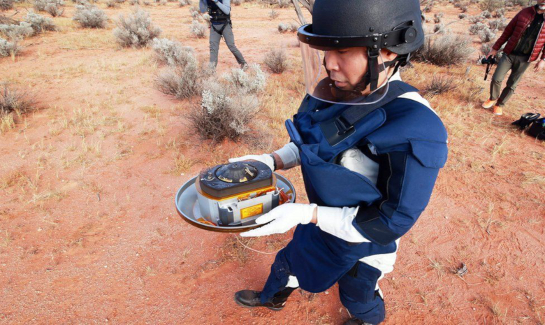 A Hayabusa2 team member carries the missions return capsule, which contains samples from asteroid Ryugu. Image: JAXA/EPA