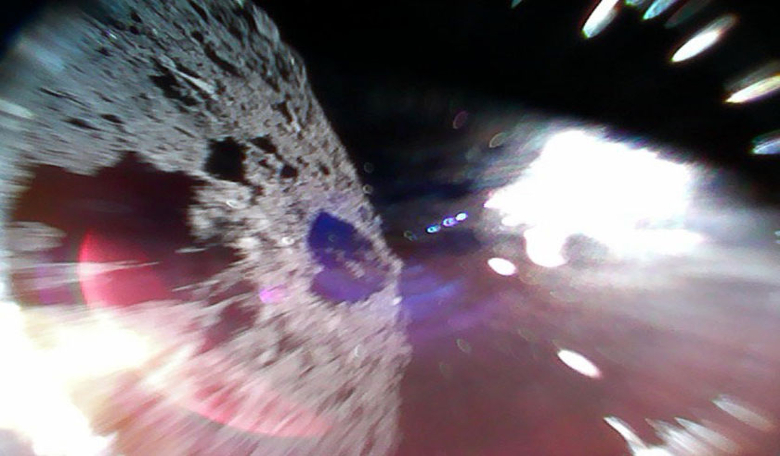 Rover in motion. Image captured by Rover-1A on 22 September while moving (during a hop) on the surface of Ryugu. The left-half of the image is the asteroid surface. The bright white region is due to sunlight. Image: JAXA