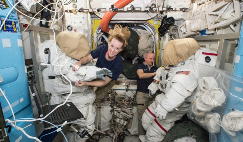 Expedition 48 crew members Kate Rubins (left) and Jeff Williams (right) of NASA outfit spacesuits inside of the Quest airlock aboard the International Space Station. Credit: NASA